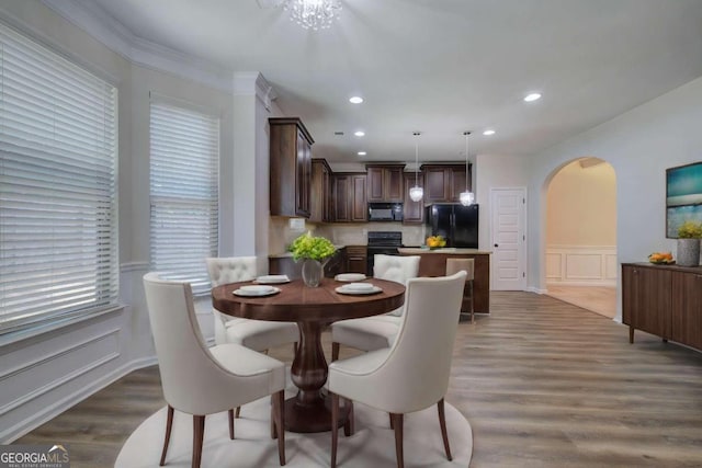 dining room with ornamental molding, dark wood-type flooring, and an inviting chandelier