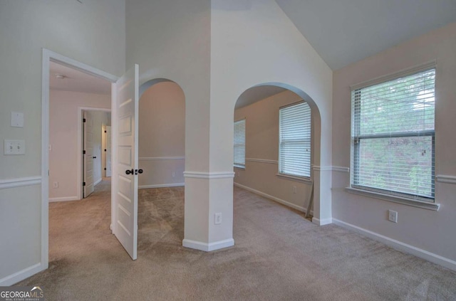 carpeted spare room with high vaulted ceiling