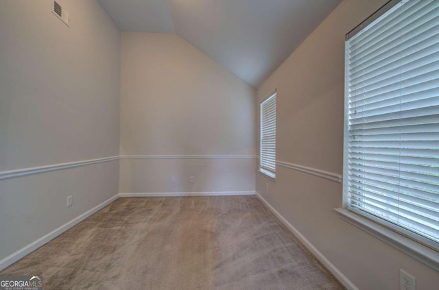 unfurnished room featuring lofted ceiling and light colored carpet