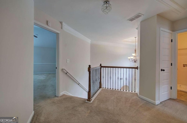 hall with ornamental molding, light carpet, and an inviting chandelier