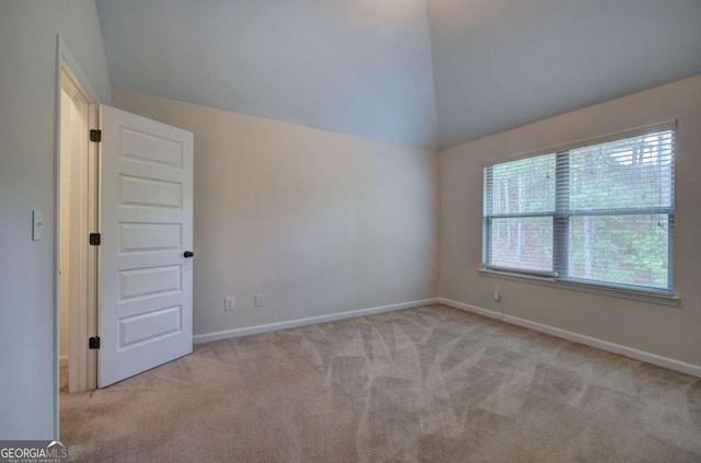 carpeted empty room featuring lofted ceiling