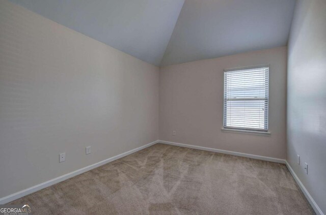 empty room with light colored carpet and vaulted ceiling