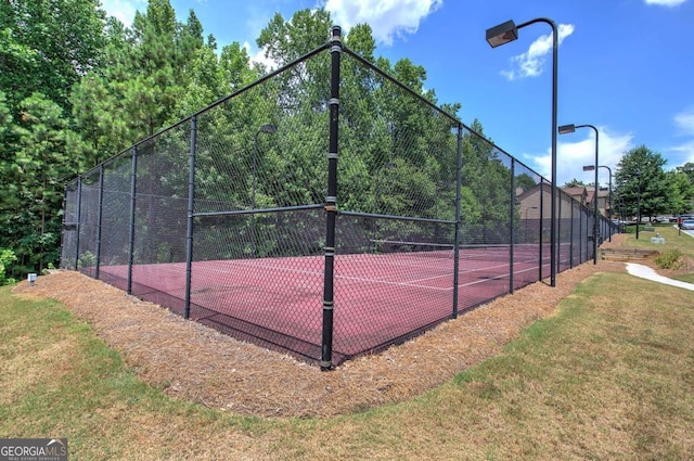 view of tennis court featuring a lawn