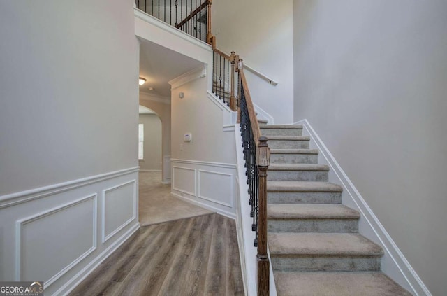 stairway with hardwood / wood-style flooring and crown molding