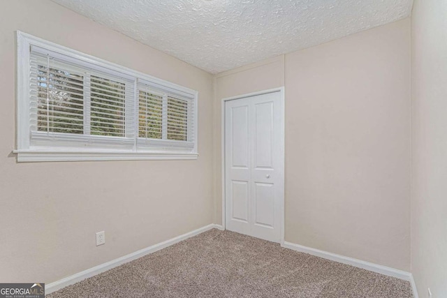 carpeted empty room featuring a textured ceiling