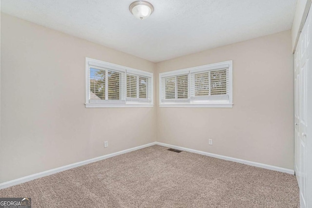 carpeted empty room featuring a textured ceiling