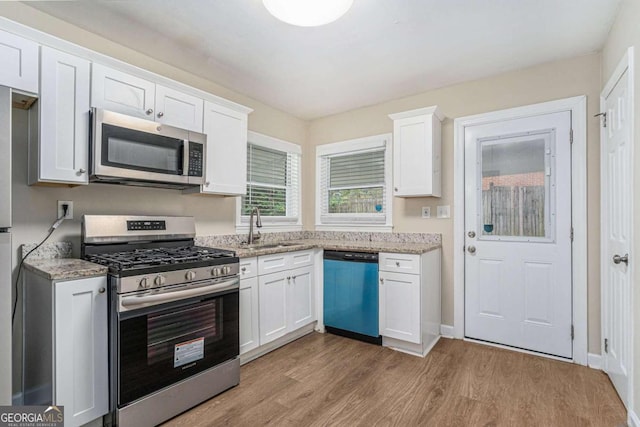 kitchen featuring light hardwood / wood-style floors, white cabinets, sink, light stone countertops, and appliances with stainless steel finishes