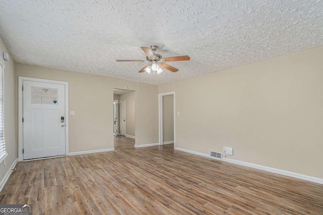 empty room featuring hardwood / wood-style floors, ceiling fan, and a textured ceiling