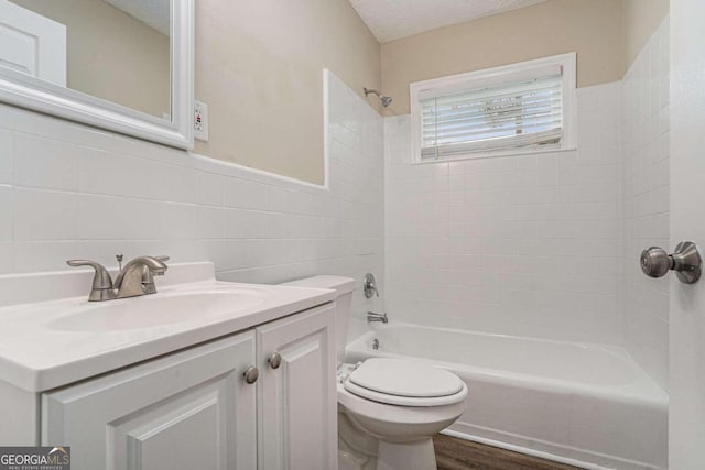 full bathroom featuring hardwood / wood-style flooring, a textured ceiling, vanity, toilet, and tile walls