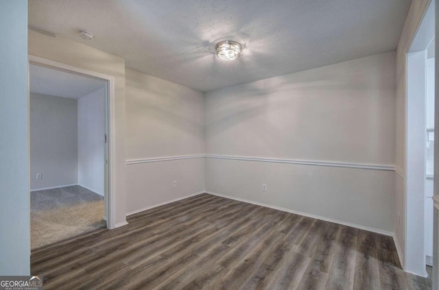 empty room with a textured ceiling and dark hardwood / wood-style floors