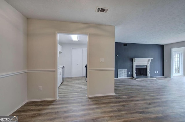 unfurnished living room with dark wood-type flooring and a textured ceiling