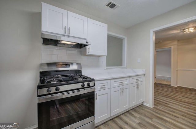 kitchen featuring light hardwood / wood-style floors, white cabinets, a textured ceiling, backsplash, and stainless steel gas range oven