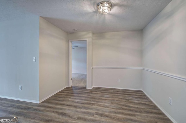 spare room featuring a textured ceiling and dark hardwood / wood-style flooring