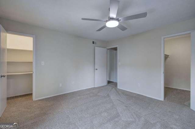 unfurnished bedroom featuring light colored carpet, ceiling fan, a walk in closet, and a closet