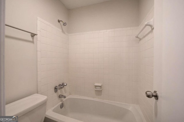 bathroom featuring toilet and tiled shower / bath