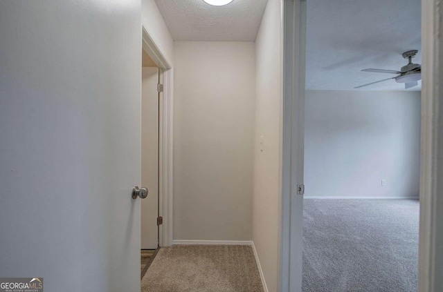 corridor with a textured ceiling and light colored carpet