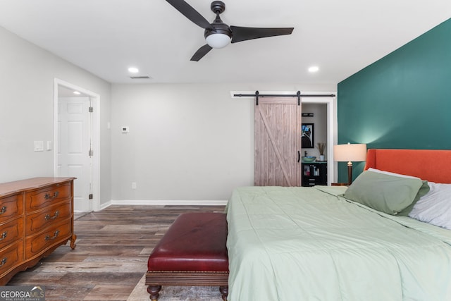 bedroom featuring ceiling fan, dark wood-type flooring, and a barn door