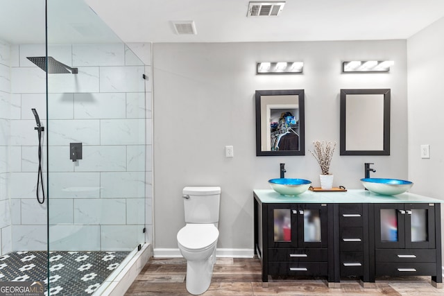 bathroom featuring wood-type flooring, vanity, a tile shower, and toilet