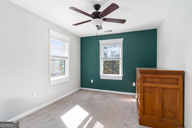 carpeted spare room featuring ceiling fan and plenty of natural light