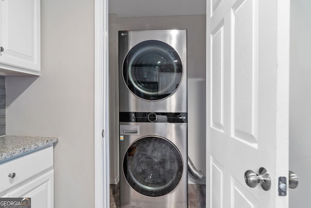 laundry room featuring stacked washer / drying machine and hardwood / wood-style flooring