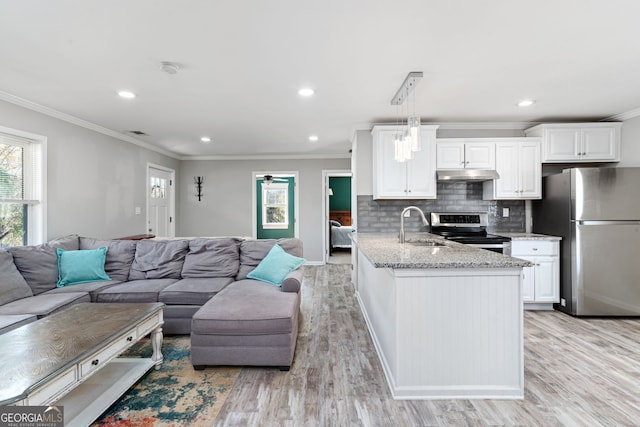 kitchen with appliances with stainless steel finishes, light wood-type flooring, sink, pendant lighting, and white cabinetry