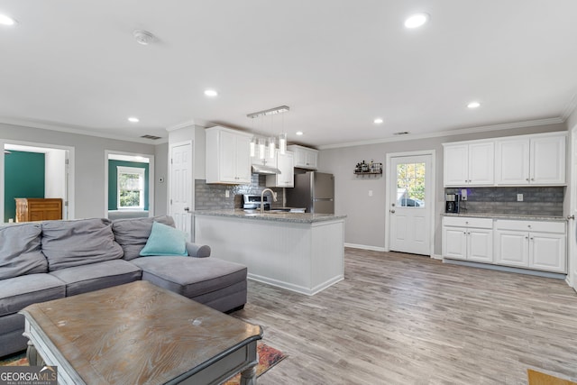 living room featuring ornamental molding, a wealth of natural light, sink, and light wood-type flooring