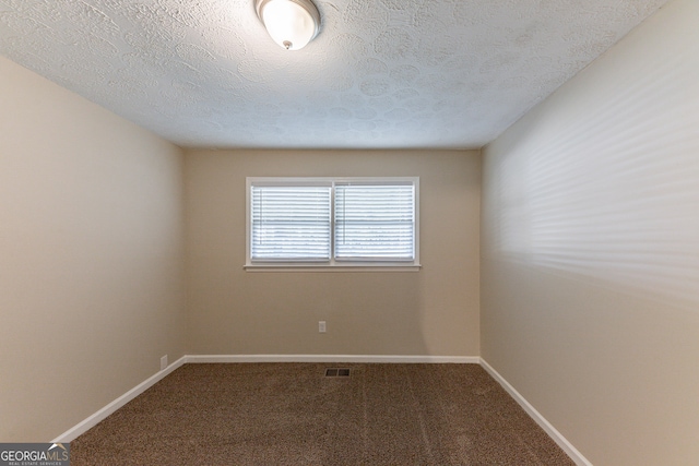 unfurnished room with carpet and a textured ceiling