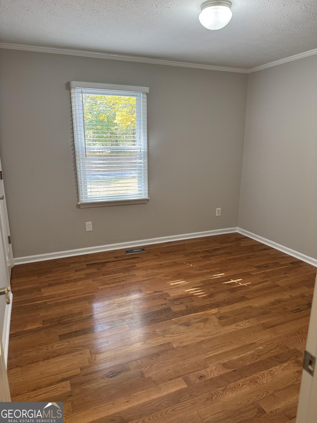 empty room featuring ornamental molding, dark hardwood / wood-style floors, and a textured ceiling