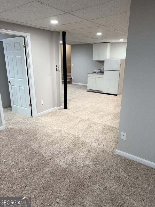 basement with light colored carpet and a drop ceiling