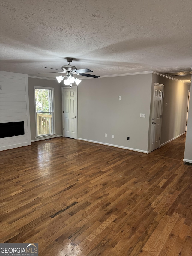 unfurnished living room with ornamental molding, dark wood-type flooring, a large fireplace, and ceiling fan