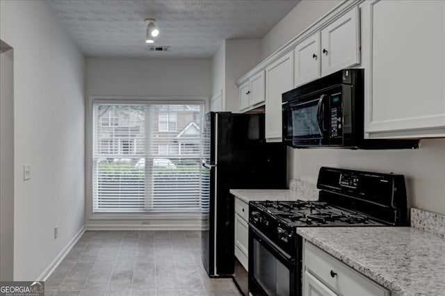 kitchen with white cabinets, black appliances, a textured ceiling, and light stone counters