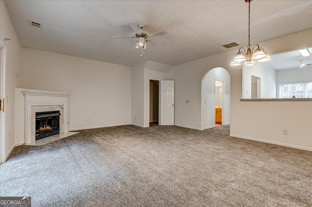 unfurnished living room featuring a premium fireplace, ceiling fan, a textured ceiling, and carpet floors