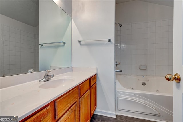 bathroom with wood-type flooring, vanity, and tiled shower / bath