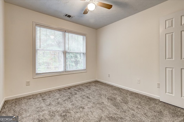 spare room with a textured ceiling, light colored carpet, and ceiling fan