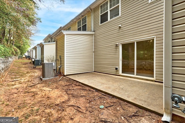 back of property with central AC and a patio