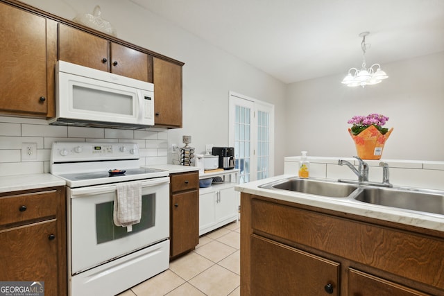 kitchen featuring light tile patterned flooring, tasteful backsplash, hanging light fixtures, white appliances, and a notable chandelier