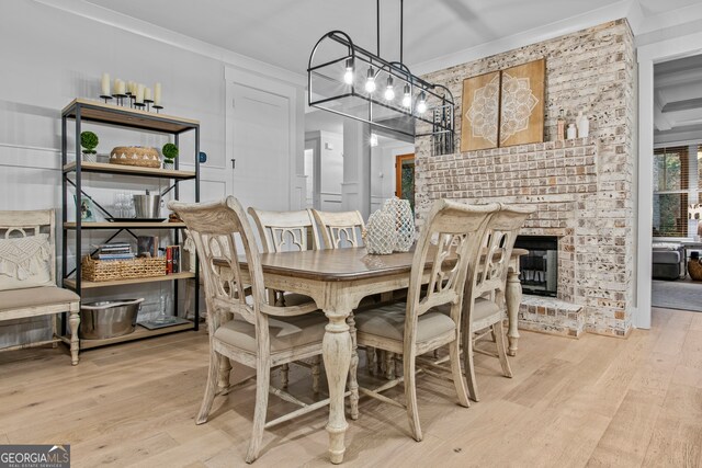 dining room featuring crown molding, light wood-type flooring, and a fireplace