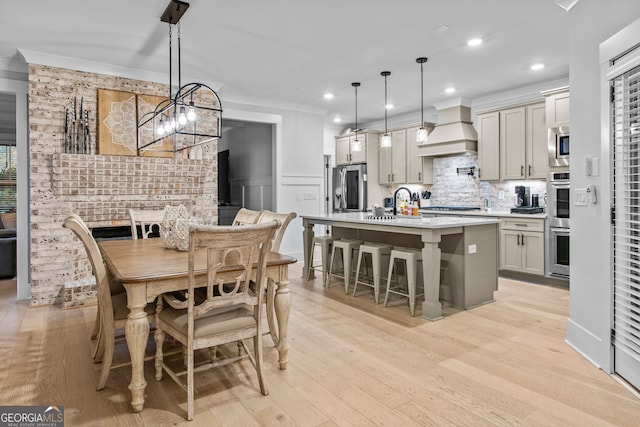 dining space with a chandelier, light wood-type flooring, and crown molding