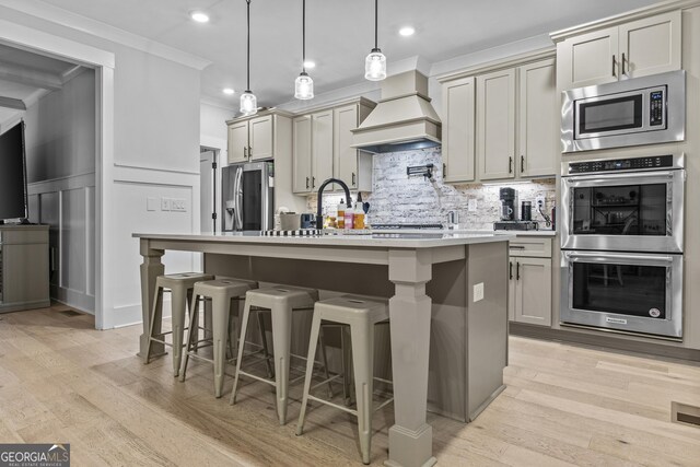 265 Federal St, Athens, GA 30607 - kitchen with appliances with stainless steel finishes, crown molding, tasteful backsplash, a kitchen island with sink, and custom exhaust hood