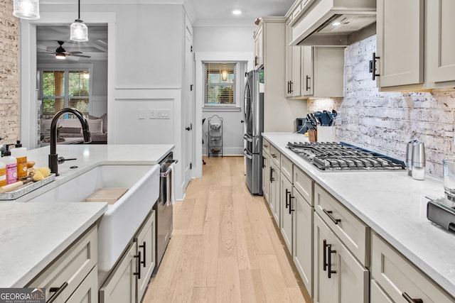 kitchen with premium range hood, light wood-type flooring, ornamental molding, appliances with stainless steel finishes, and decorative light fixtures