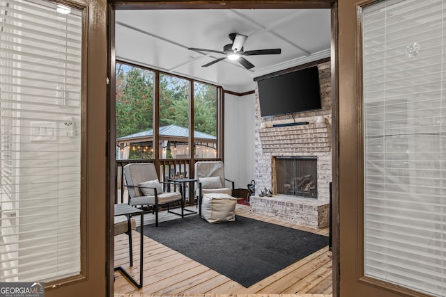 sunroom / solarium featuring ceiling fan and a fireplace