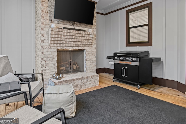 living room with a fireplace, light wood-type flooring, and crown molding