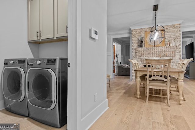 laundry area with cabinets, light wood-type flooring, ornamental molding, and separate washer and dryer