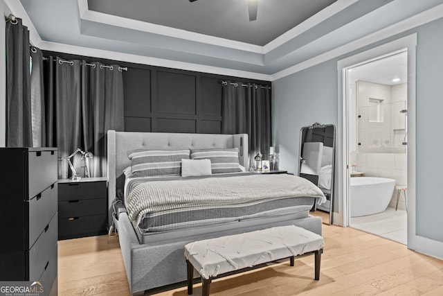 bedroom with ceiling fan, a raised ceiling, connected bathroom, and light hardwood / wood-style flooring