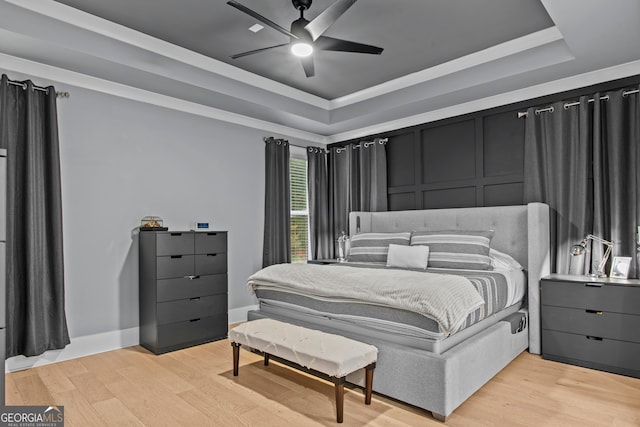 bedroom featuring a tray ceiling, ceiling fan, crown molding, and light hardwood / wood-style floors