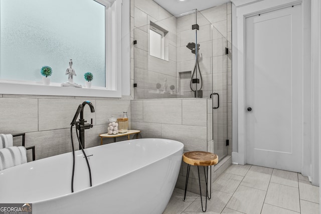 bathroom with tile patterned floors, separate shower and tub, and tile walls