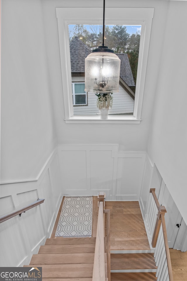 staircase with wood-type flooring and an inviting chandelier