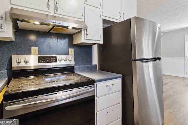 117 Neal Ave, Stockbridge, GA 30281 - kitchen with stainless steel appliances, under cabinet range hood, white cabinetry, light wood-style floors, and dark countertops
