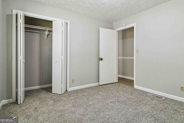 unfurnished bedroom featuring light carpet, a textured ceiling, and a closet