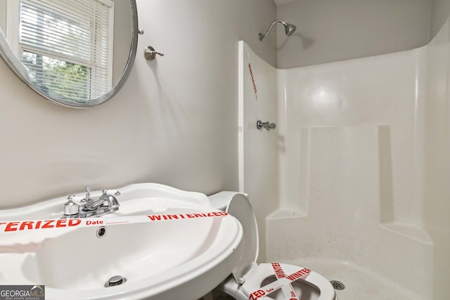 bathroom featuring toilet, a shower, and sink